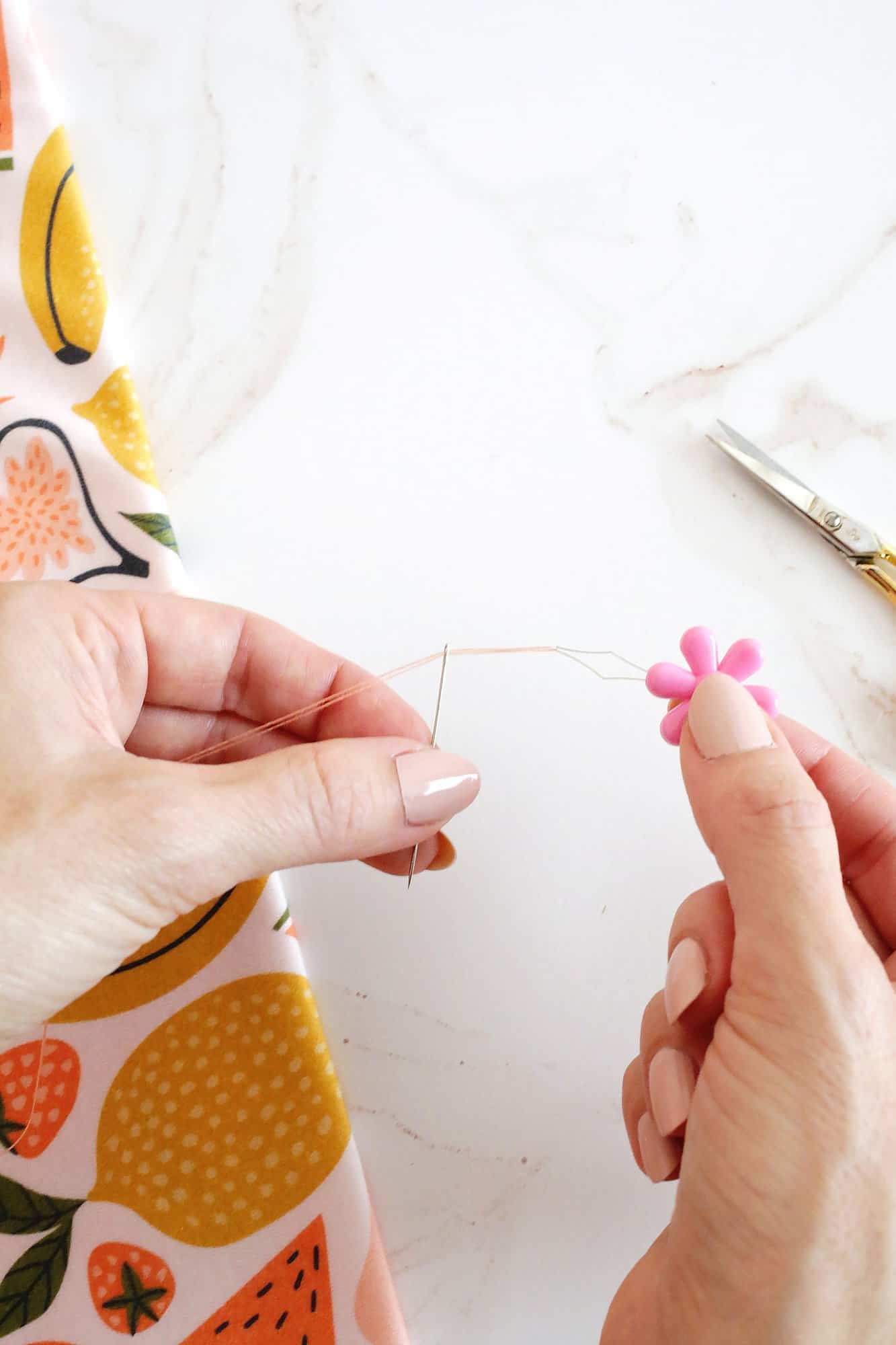 hand pulling a thread through a needle with a needle threader